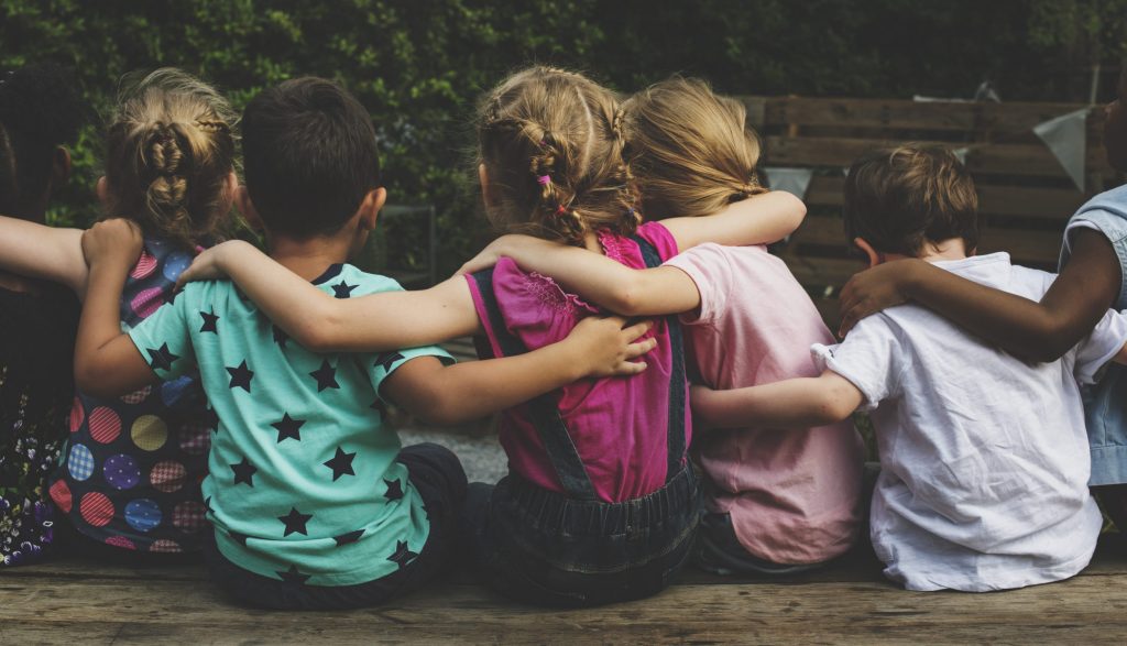 Eine Gruppe Kindergartenkinder sitzt zusammen und die Kinder umarmen sich.